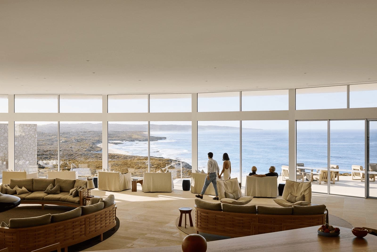 Guests looking out over the ocean from a lounge with tall windows