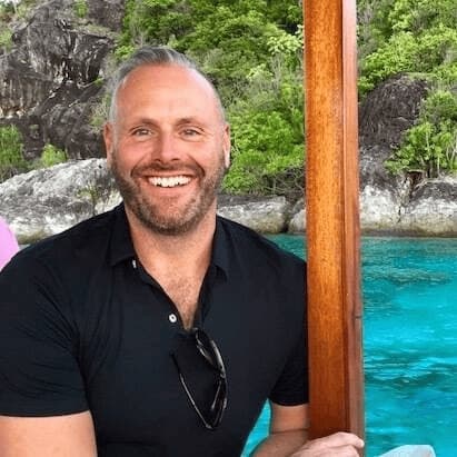 Portrait of Stuart Reay on a boat by a turquoise bay