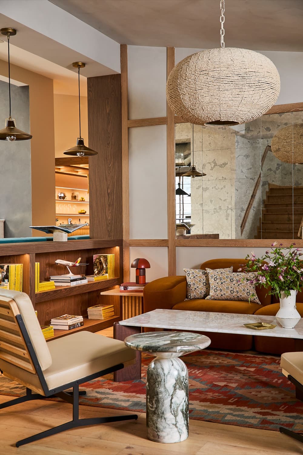 A warm hotel lounge with a woven pendant lamp and a marble table