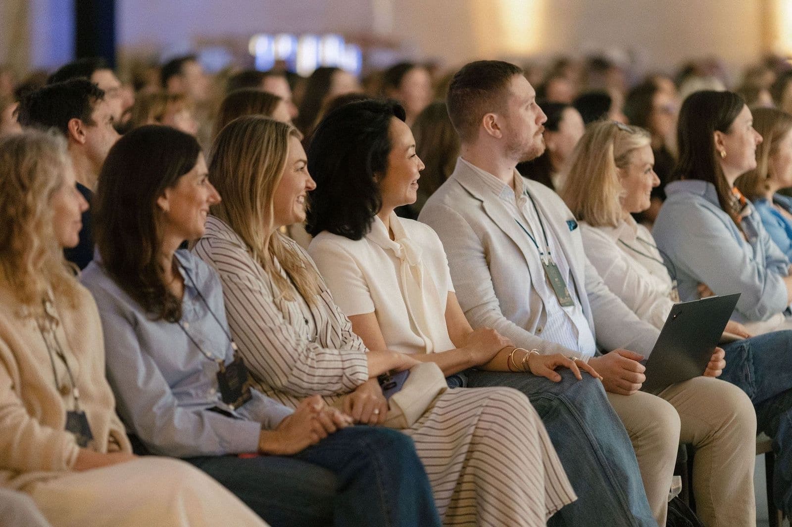 Smiling travel advisors seated in a crowded event hall