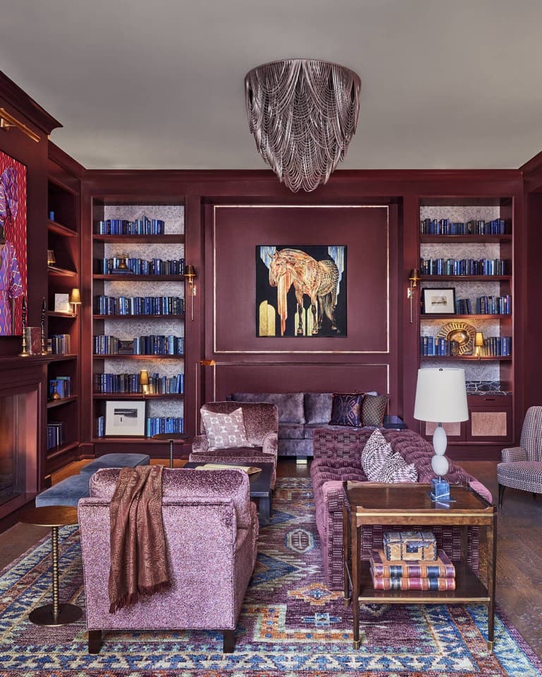 A deep red library lounge with shelves and a chandelier