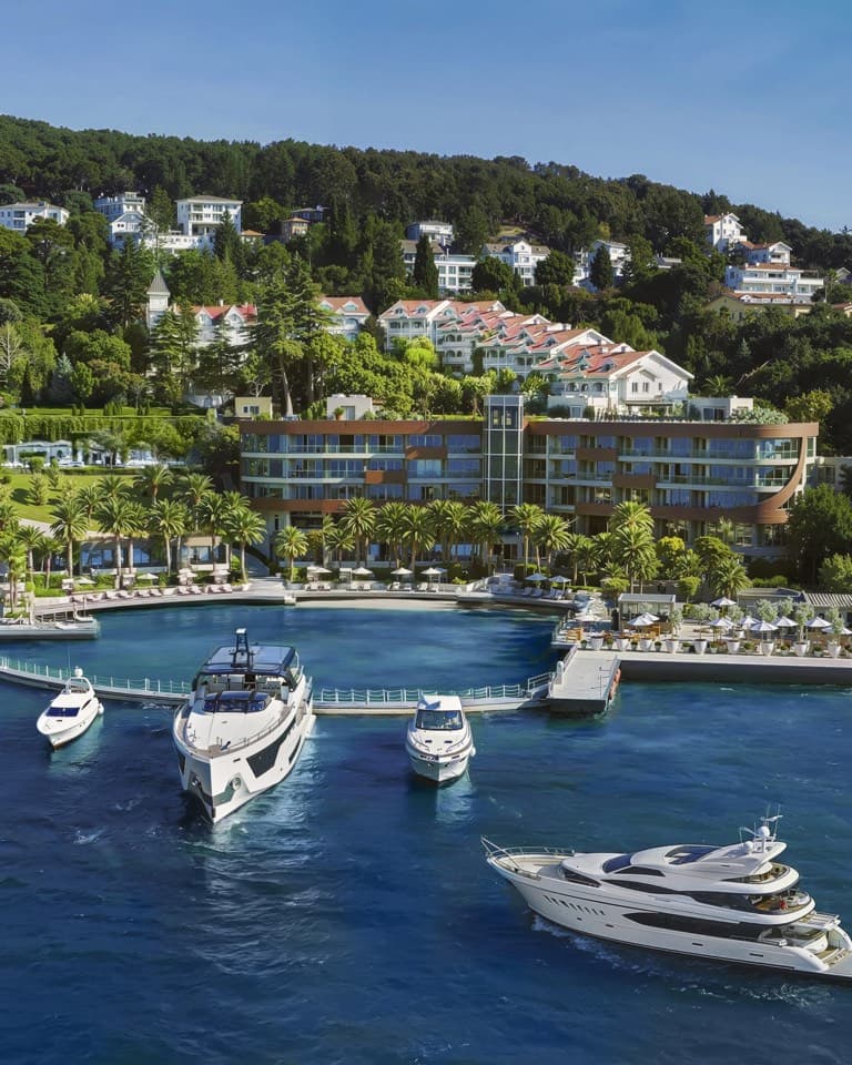 A hillside resort above a harbour with a white yacht