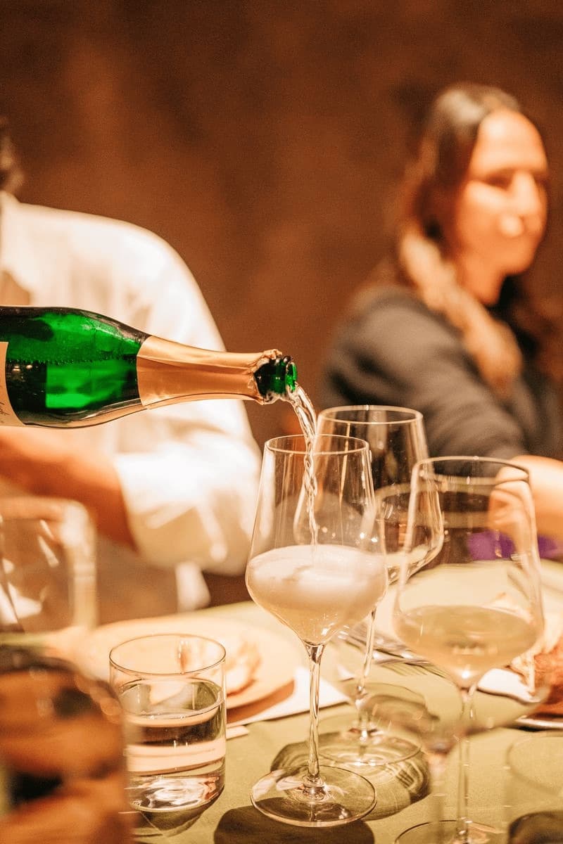 Champagne poured into glasses at a candlelit table